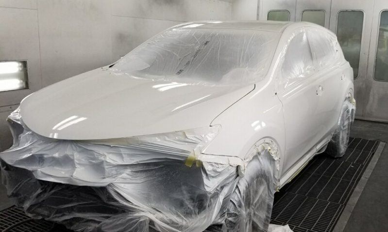 A newly painted white car is drying in a paint room at Cool Springs Collision Center